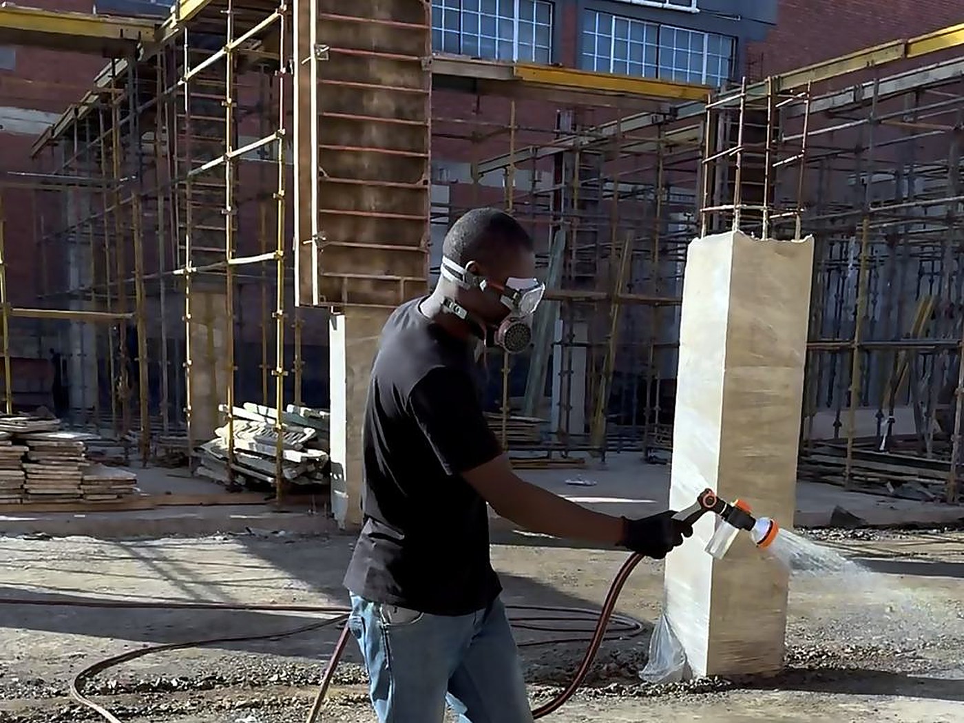 Registered operator in respirator and full protective equipment on a commercial site.
