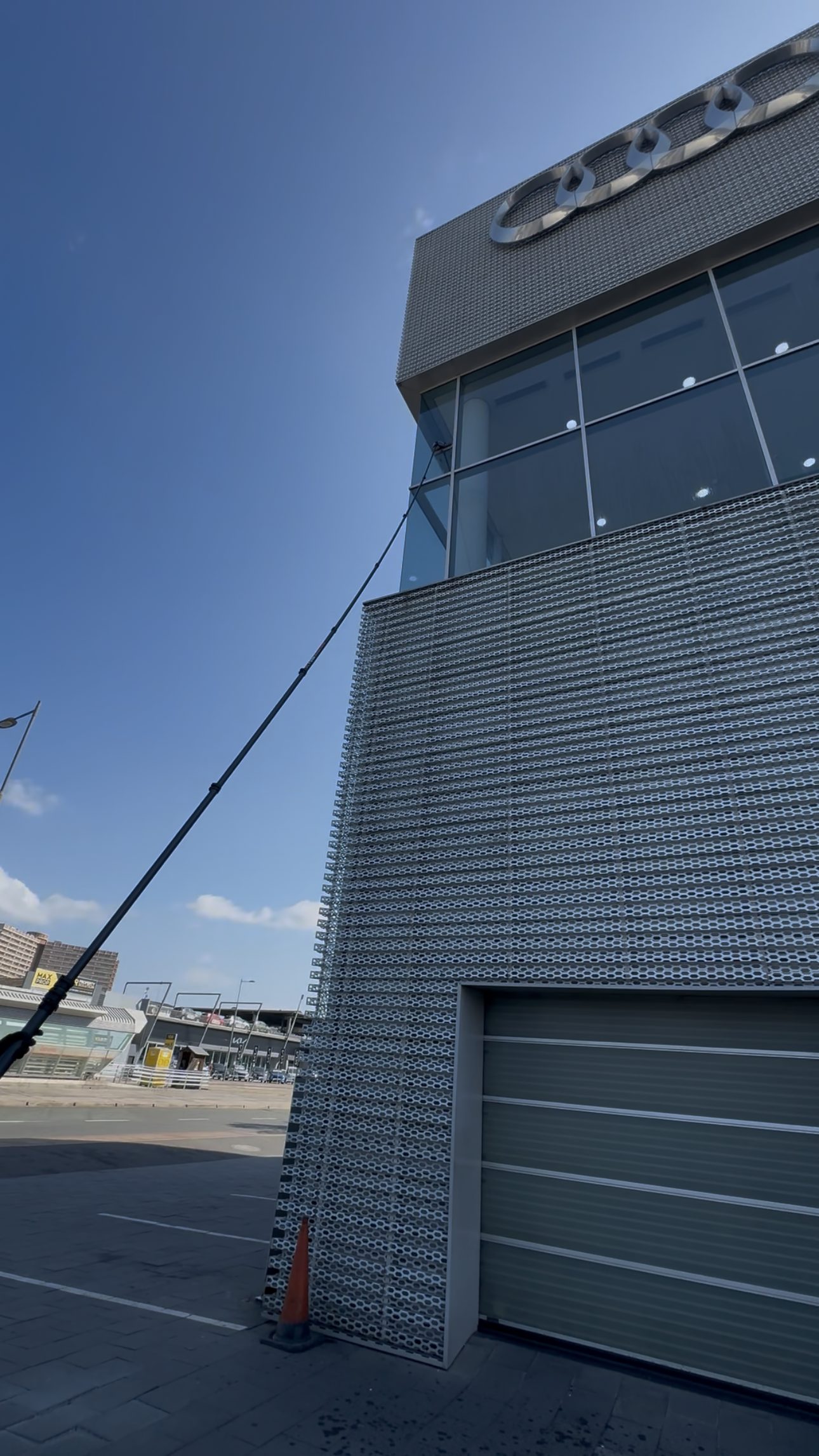 Water fed pole reaching a perforated facade from ground level.
